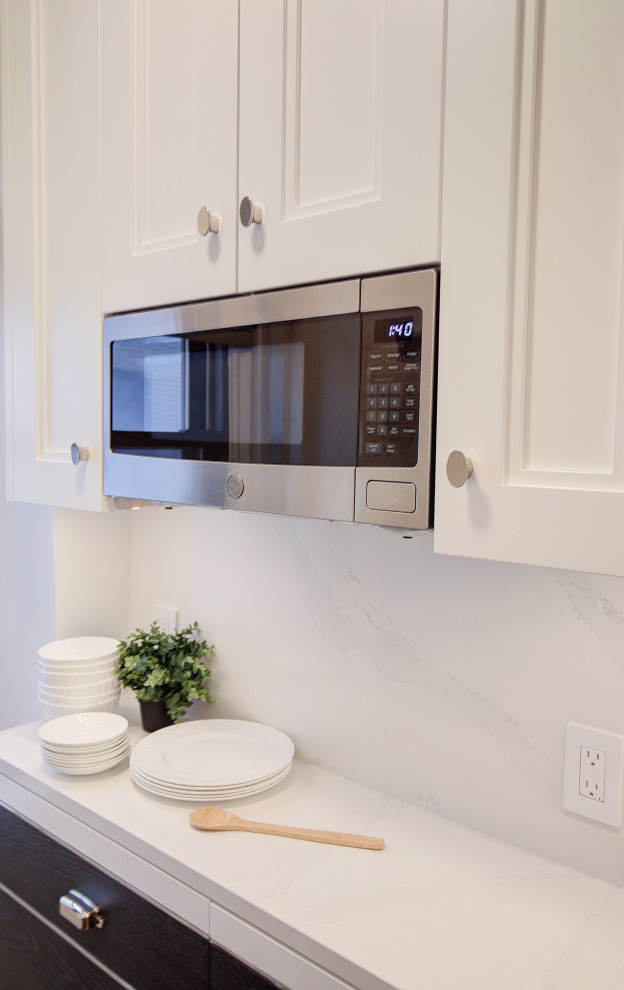 Modern inredning av ett litet vit vitt kök, med en enkel diskho, släta luckor, vita skåp, vitt stänkskydd, stänkskydd i keramik, integrerade vitvaror, mörkt trägolv och brunt golv