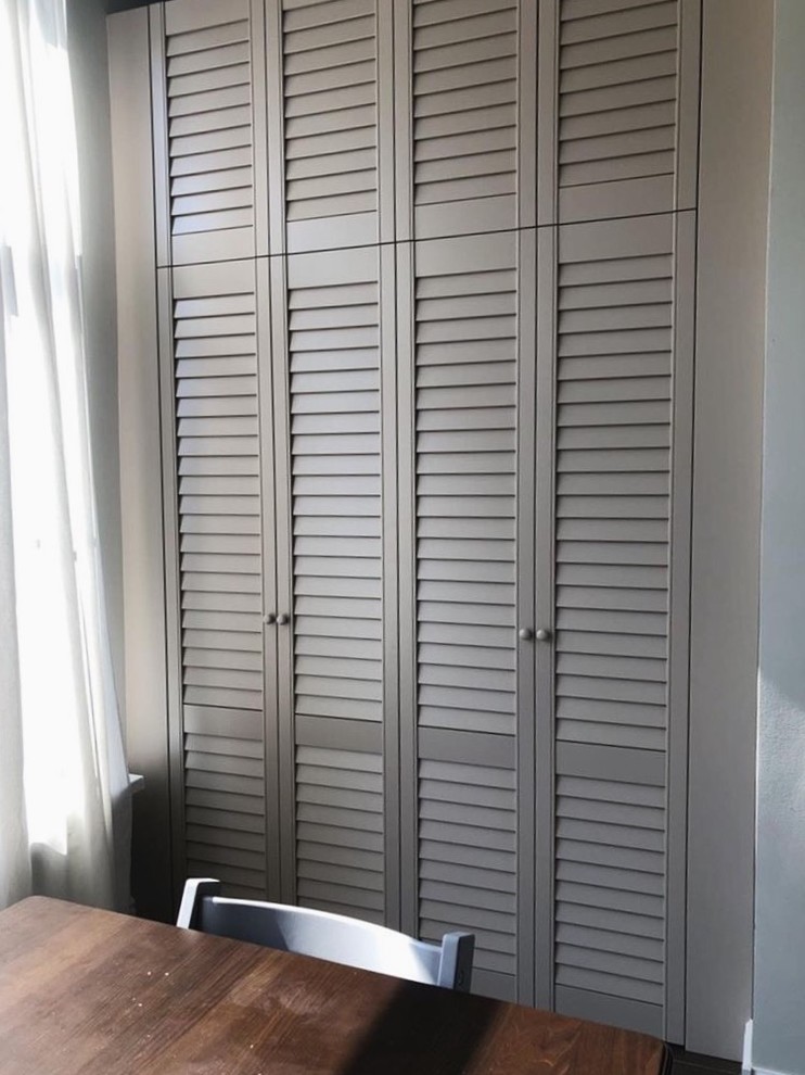 Photo of a mid-sized transitional built-in wardrobe in Other with louvered cabinets and beige cabinets.