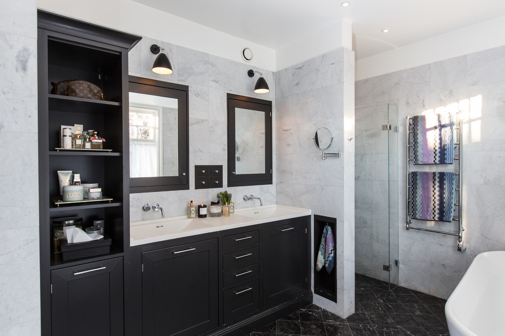 Design ideas for a large transitional master bathroom in Stockholm with shaker cabinets, black cabinets, a freestanding tub, a curbless shower, gray tile, grey walls, an integrated sink and a hinged shower door.