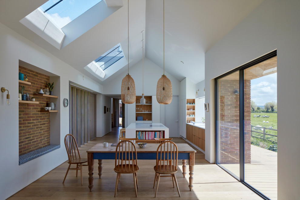 Design ideas for a contemporary open plan dining room in Hertfordshire with white walls, light hardwood flooring, beige floors and a vaulted ceiling.