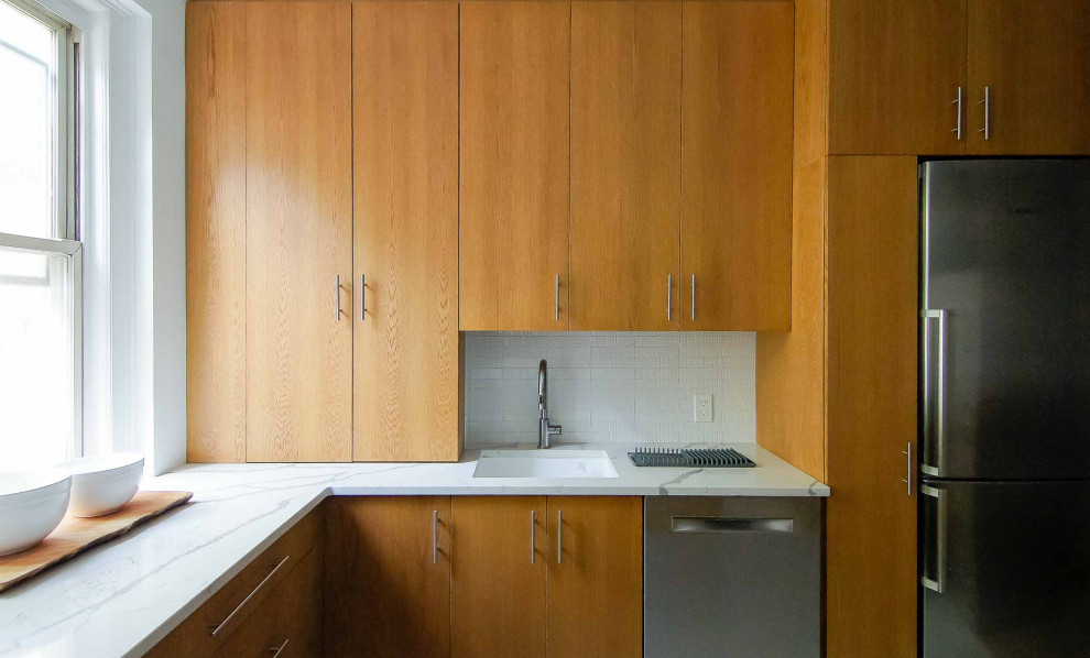 Foto på ett litet retro vit kök, med en undermonterad diskho, släta luckor, skåp i mellenmörkt trä, bänkskiva i kvartsit, vitt stänkskydd, stänkskydd i keramik, rostfria vitvaror och en halv köksö