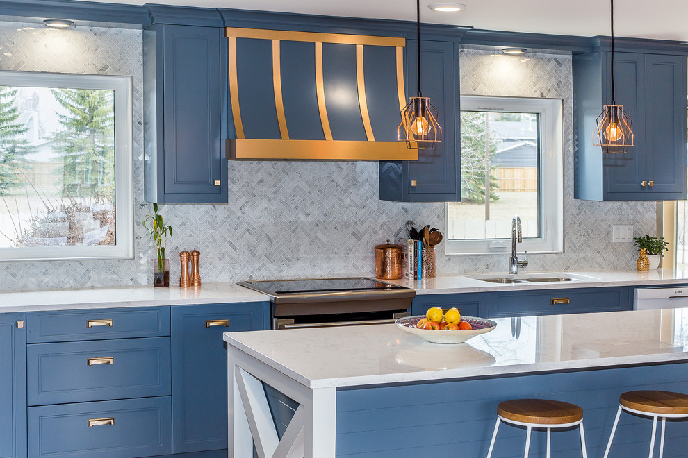 Large transitional l-shaped medium tone wood floor and brown floor enclosed kitchen photo with a double-bowl sink, recessed-panel cabinets, blue cabinets, marble countertops, white backsplash, marble backsplash, stainless steel appliances and an island
