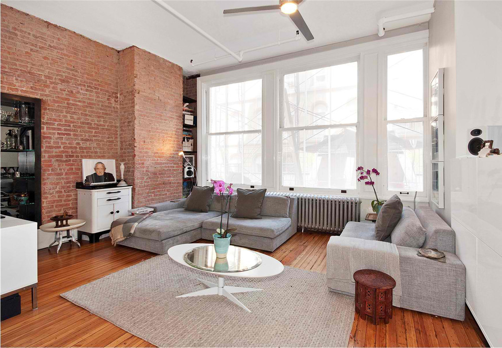 Large contemporary enclosed family room in New York with white walls, medium hardwood floors, no fireplace and brown floor.
