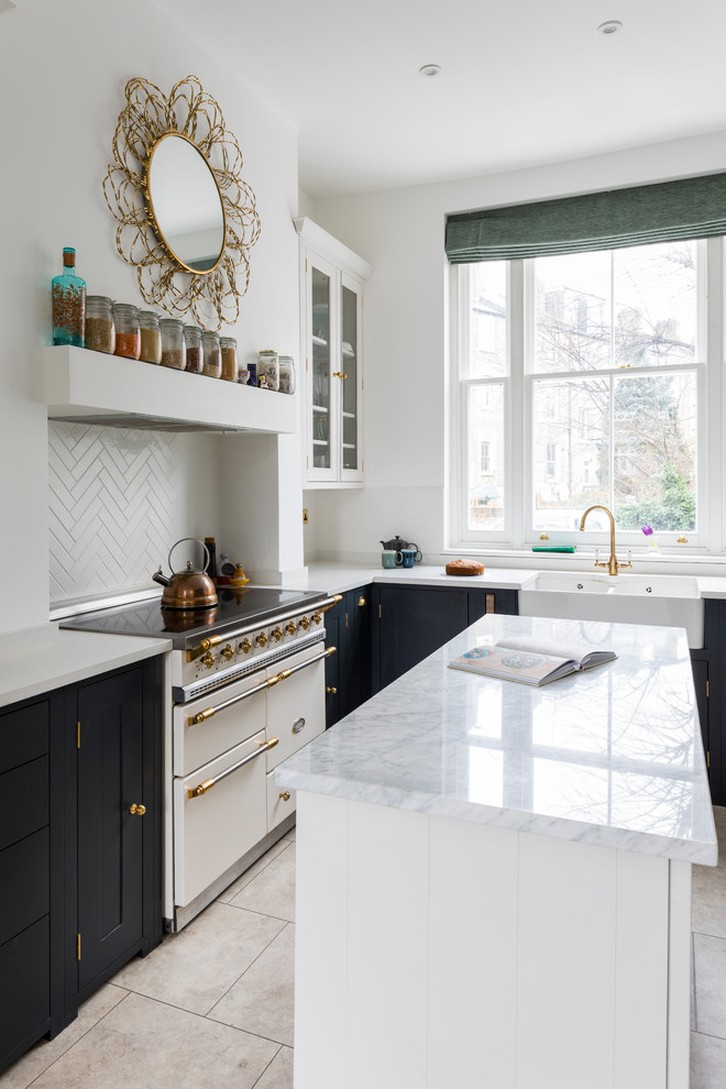 Small transitional l-shaped eat-in kitchen in London with a farmhouse sink, shaker cabinets, black cabinets, quartzite benchtops, limestone floors, with island and beige floor.