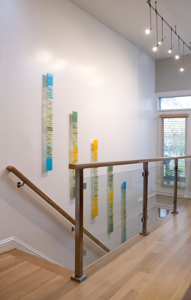 Immagine di una scala a rampa dritta minimalista di medie dimensioni con pedata in legno, alzata in legno e parapetto in vetro