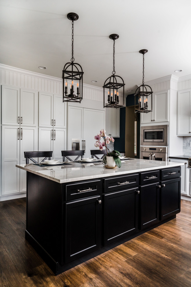 Photo of a large transitional l-shaped eat-in kitchen in Philadelphia with flat-panel cabinets, white cabinets, granite benchtops, white splashback, marble splashback, stainless steel appliances, vinyl floors, with island, brown floor, black benchtop and a farmhouse sink.
