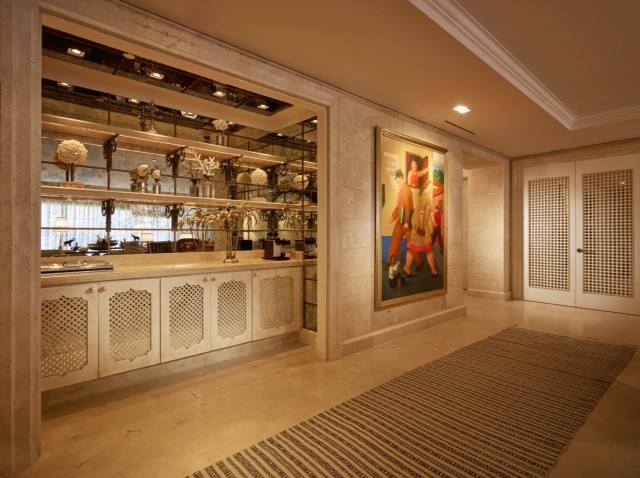 This is an example of a mid-sized transitional single-wall wet bar in Miami with beige cabinets, limestone benchtops, mirror splashback, linoleum floors and beige floor.