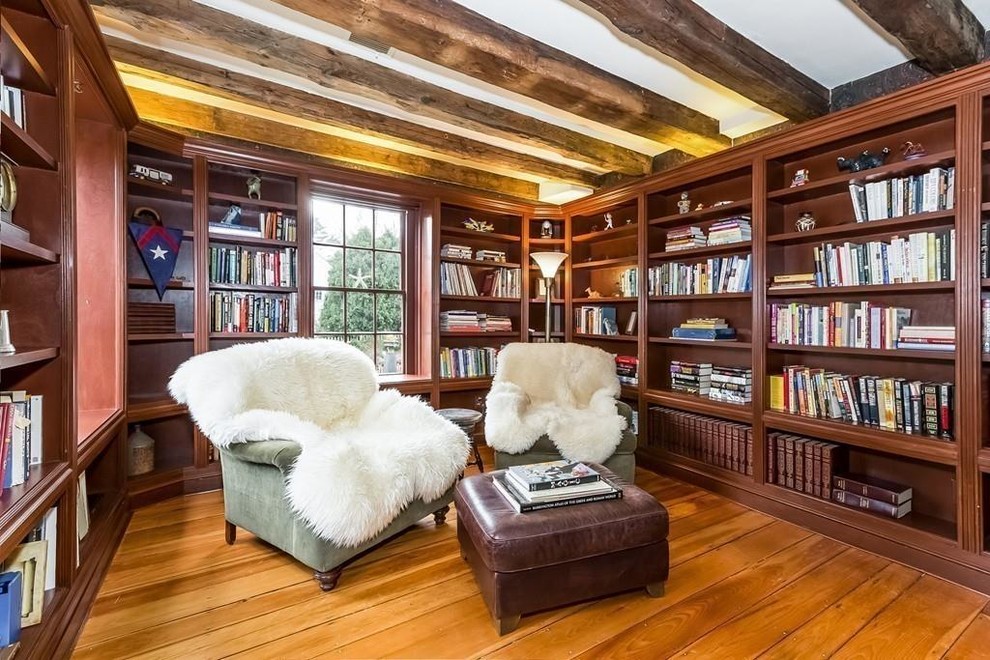 This is an example of a traditional home office in Philadelphia with a library, brown walls, medium hardwood floors and brown floor.