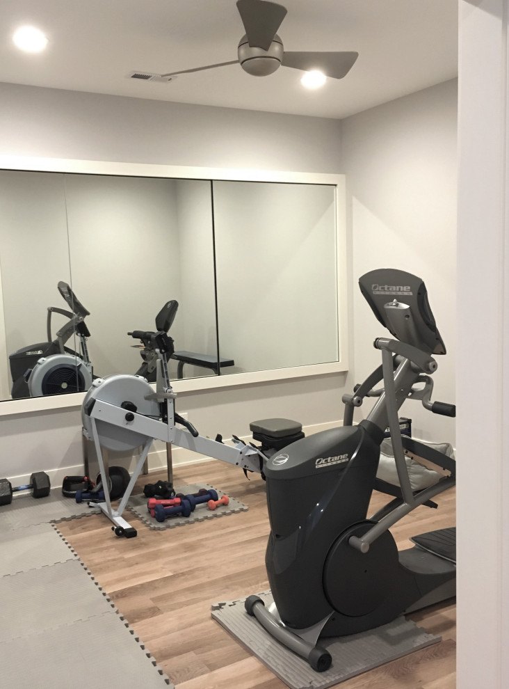 This is an example of a small country home weight room in Minneapolis with grey walls, light hardwood floors and brown floor.