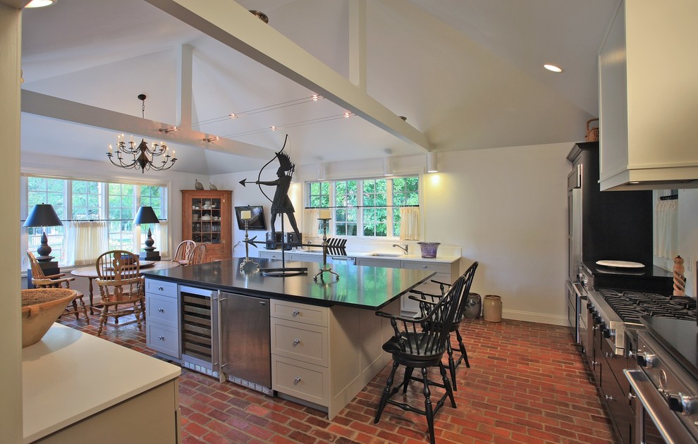 This is an example of a large traditional l-shaped eat-in kitchen in Baltimore with an undermount sink, shaker cabinets, black cabinets, quartz benchtops, stainless steel appliances, brick floors, with island and red floor.