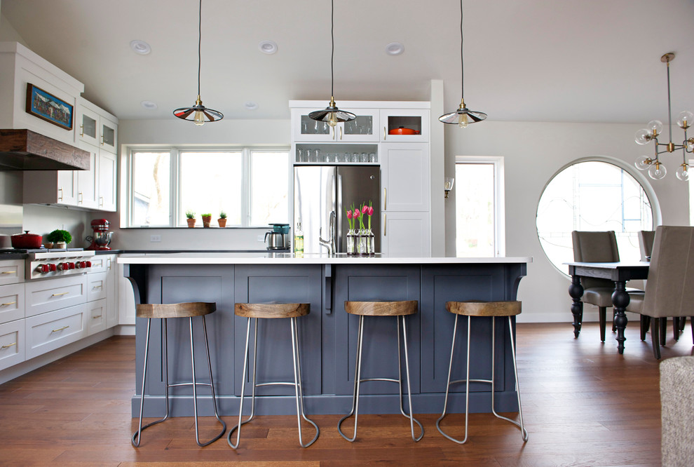 Inspiration for a large transitional l-shaped medium tone wood floor open concept kitchen remodel in Indianapolis with an undermount sink, shaker cabinets, white cabinets, quartz countertops, gray backsplash, stainless steel appliances and an island