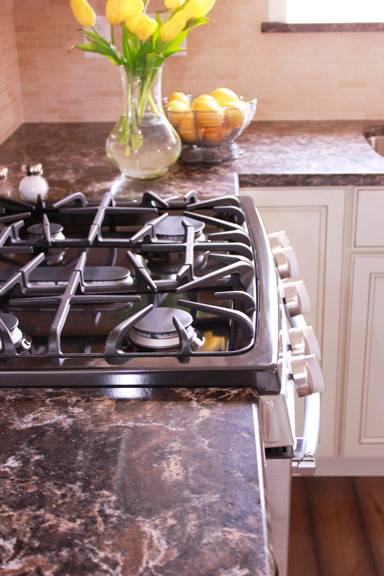 Small transitional u-shaped dark wood floor enclosed kitchen photo with an undermount sink, beaded inset cabinets, white cabinets, quartzite countertops, beige backsplash and stainless steel appliances