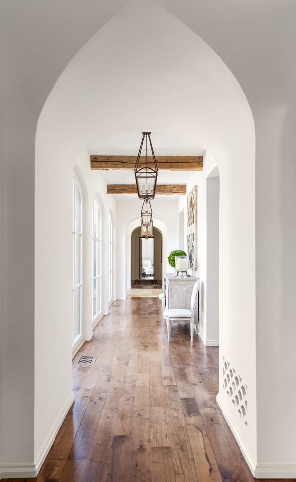 Design ideas for a mediterranean hallway in Dallas with white walls and medium hardwood floors.
