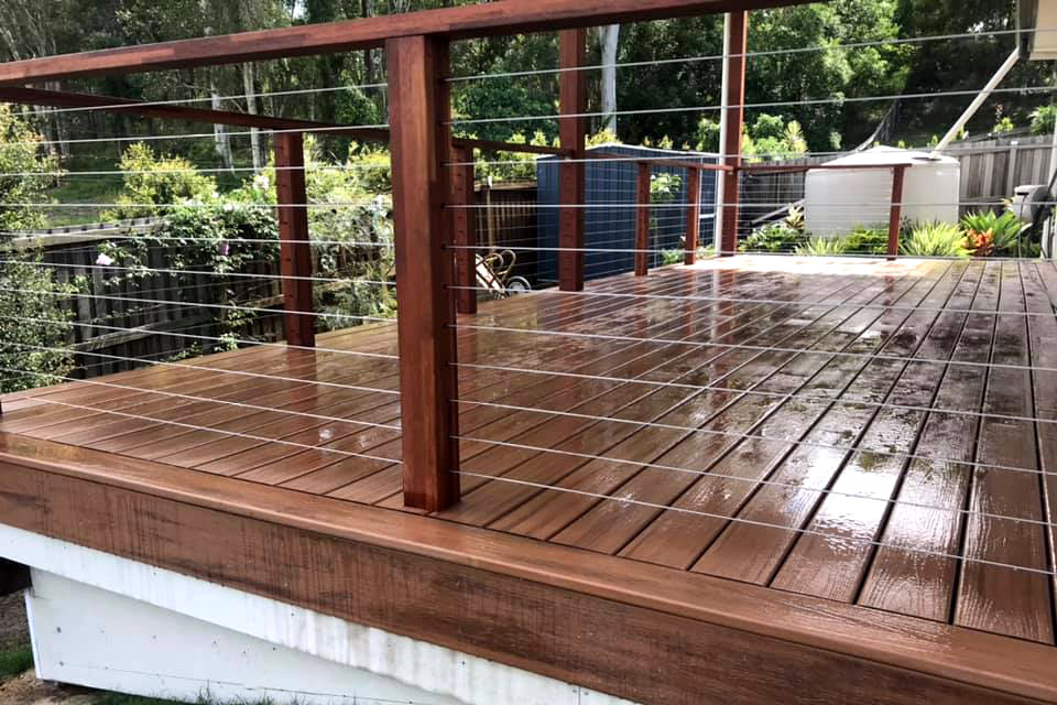 Design ideas for a mid-sized backyard and ground level deck in Townsville with mixed railing.