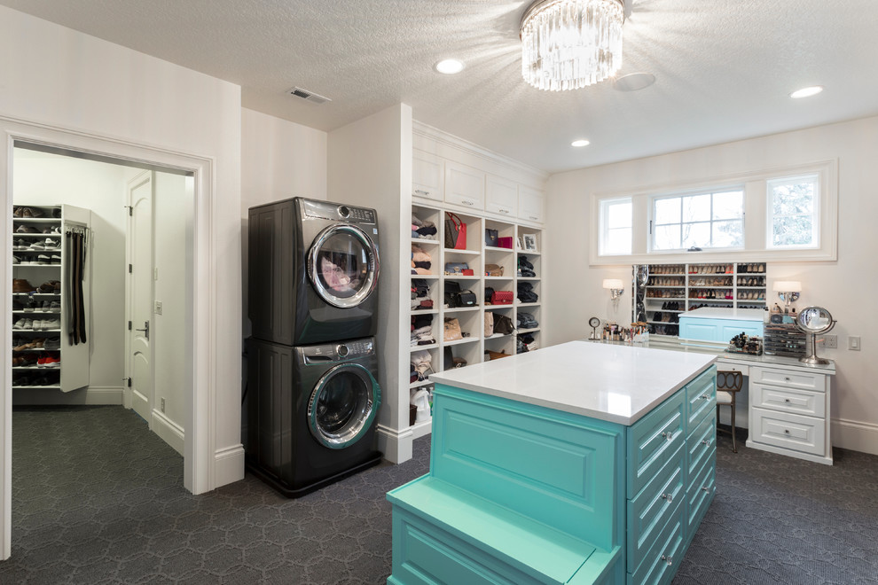 This is an example of an expansive transitional gender-neutral walk-in wardrobe in Portland with beaded inset cabinets, blue cabinets, carpet and grey floor.