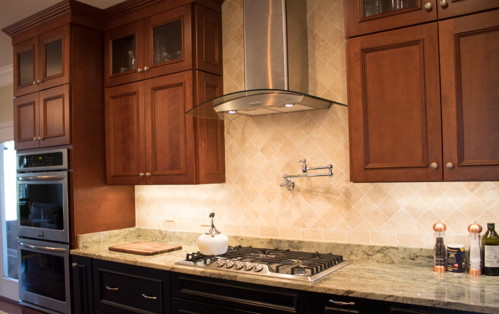 Example of a large transitional l-shaped dark wood floor and brown floor enclosed kitchen design in DC Metro with a double-bowl sink, raised-panel cabinets, dark wood cabinets, granite countertops, beige backsplash, limestone backsplash, stainless steel appliances and an island