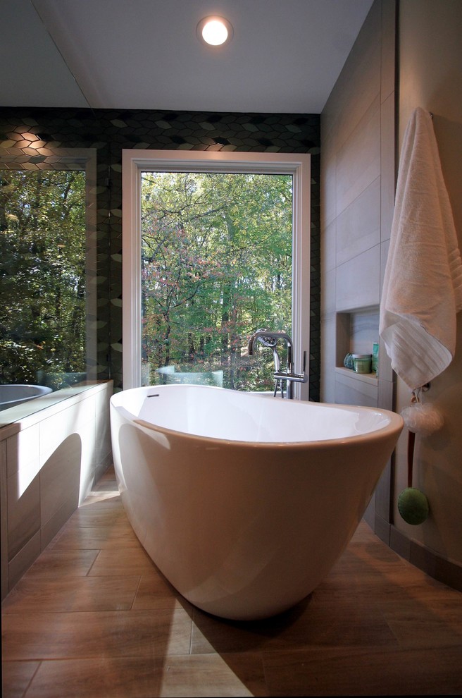 Inspiration for a mid-sized asian master bathroom in DC Metro with flat-panel cabinets, light wood cabinets, a japanese tub, a corner shower, a one-piece toilet, green tile, porcelain tile, green walls, porcelain floors, a vessel sink, engineered quartz benchtops, brown floor and a hinged shower door.
