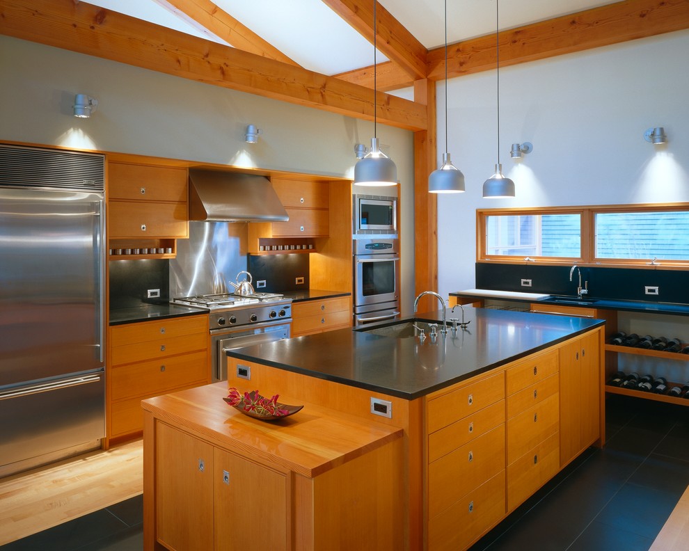 Photo of a large contemporary u-shaped open plan kitchen in Portland Maine with an undermount sink, flat-panel cabinets, medium wood cabinets, black splashback, stone slab splashback, stainless steel appliances, granite benchtops, slate floors, with island and black floor.