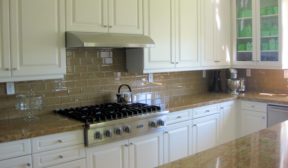 Example of a transitional eat-in kitchen design with white cabinets, beige backsplash, glass tile backsplash and stainless steel appliances