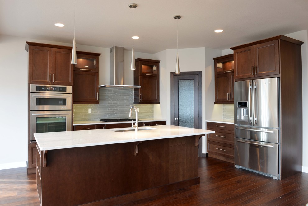 Inspiration for a large transitional l-shaped dark wood floor and brown floor eat-in kitchen remodel with an undermount sink, flat-panel cabinets, dark wood cabinets, quartz countertops, gray backsplash, glass sheet backsplash, stainless steel appliances and an island