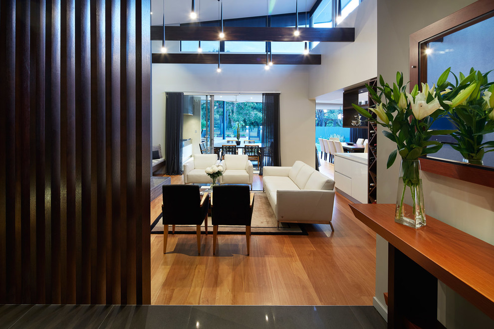 This is an example of a contemporary open concept family room in Other with brown walls and light hardwood floors.