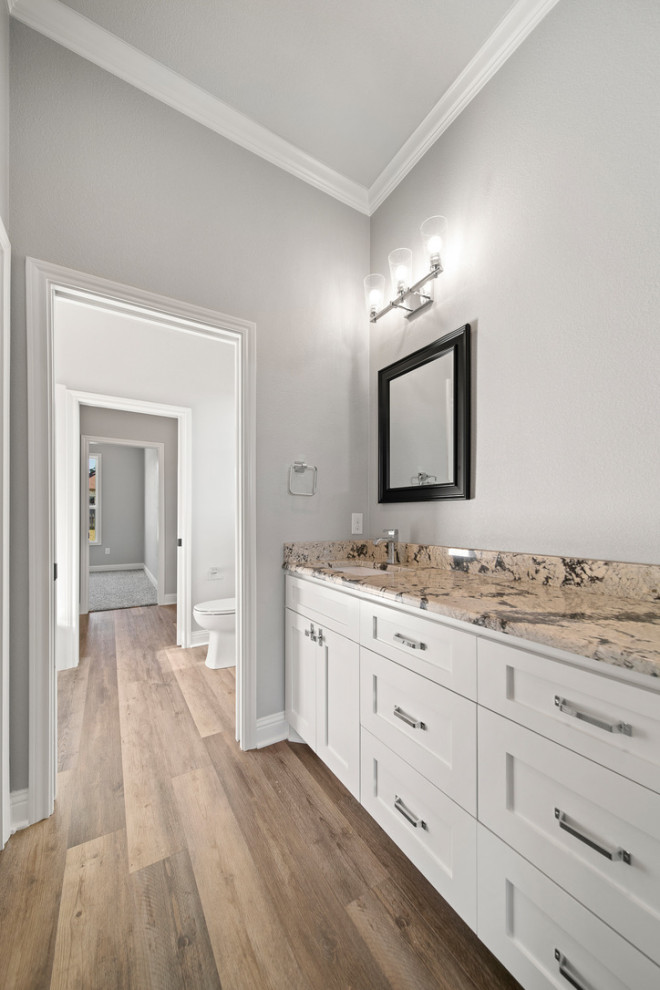 Large traditional kids bathroom in Austin with shaker cabinets, white cabinets, an alcove tub, a shower/bathtub combo, a one-piece toilet, grey walls, vinyl floors, a drop-in sink, granite benchtops, brown floor, a shower curtain, brown benchtops, an enclosed toilet, a single vanity and a built-in vanity.