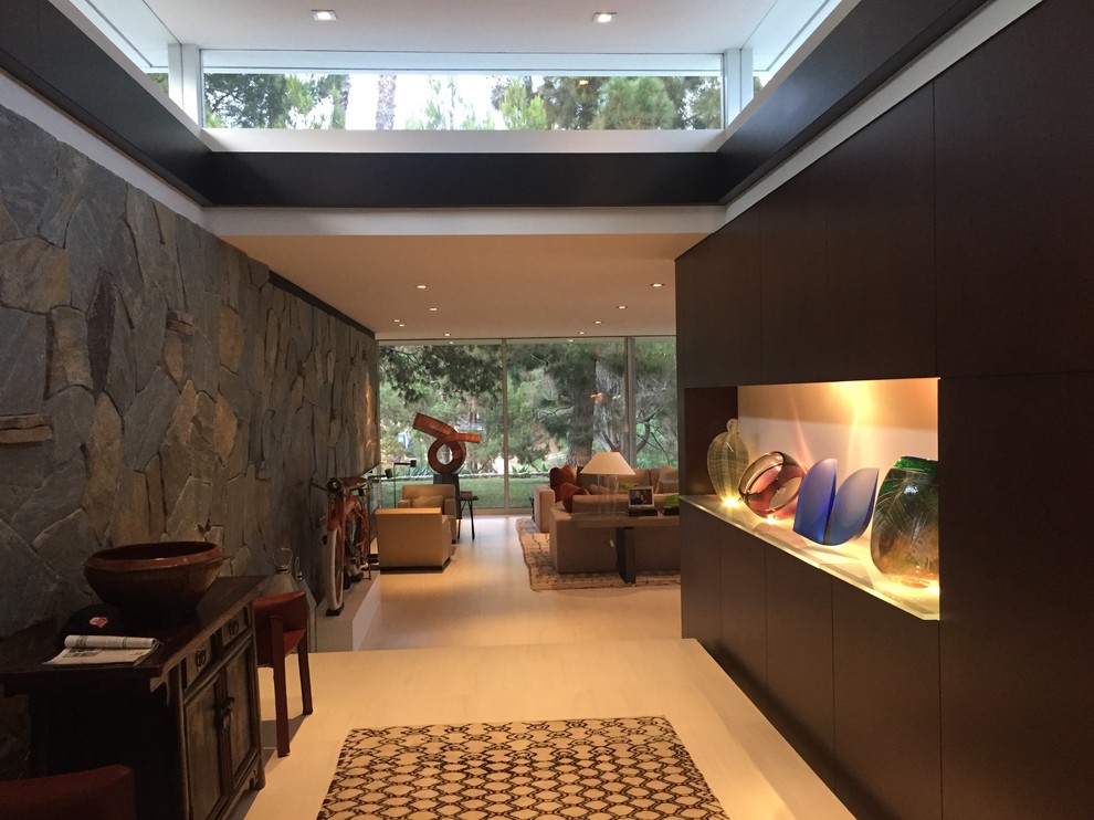 Example of a mid-sized 1950s open concept porcelain tile and beige floor family room design in Los Angeles with beige walls, a two-sided fireplace and a stone fireplace