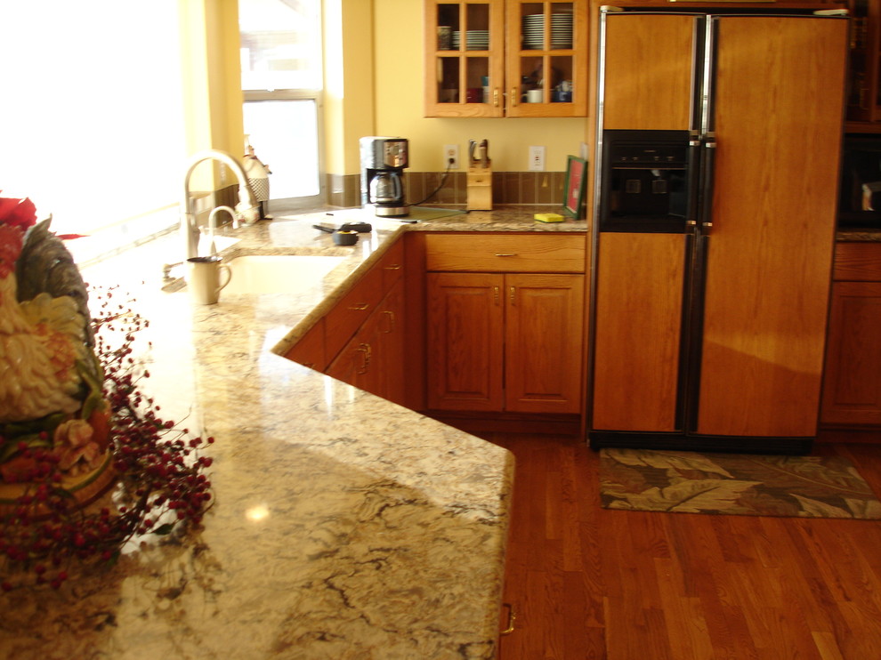 Example of a large transitional l-shaped medium tone wood floor eat-in kitchen design in Seattle with medium tone wood cabinets, beige backsplash, paneled appliances, yellow walls, an island, a single-bowl sink, raised-panel cabinets, granite countertops and glass tile backsplash