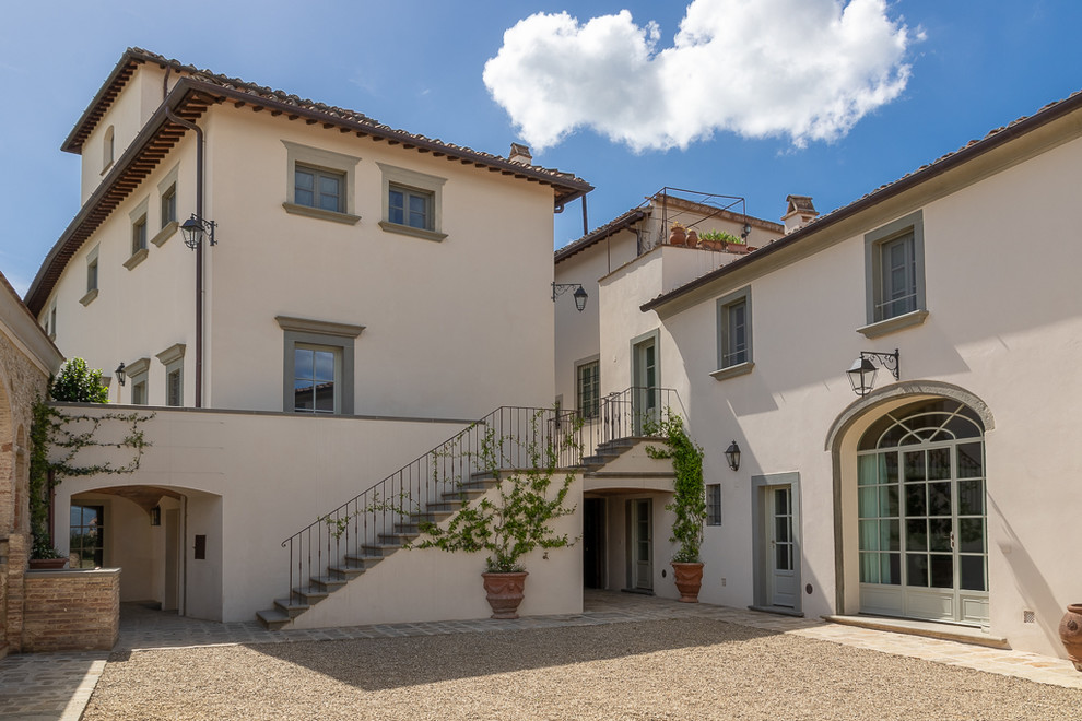 This is an example of a large traditional three-storey beige exterior in Florence with a hip roof and a tile roof.