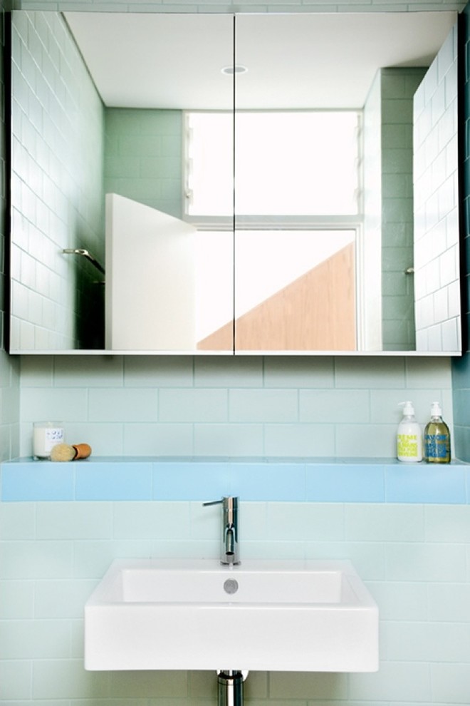 Design ideas for a small modern 3/4 bathroom in Sydney with a wall-mount sink, flat-panel cabinets, tile benchtops, an alcove shower, blue tile, ceramic tile, blue walls and porcelain floors.