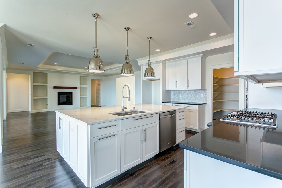 This is an example of a mid-sized modern l-shaped open plan kitchen in Seattle with an undermount sink, shaker cabinets, white cabinets, quartz benchtops, grey splashback, mosaic tile splashback, stainless steel appliances, dark hardwood floors and with island.