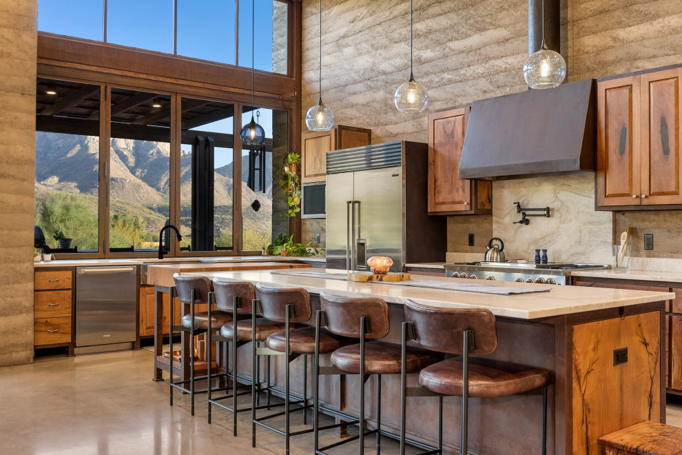 Open concept kitchen - rustic l-shaped concrete floor, beige floor and wood ceiling open concept kitchen idea with an undermount sink, shaker cabinets, brown cabinets, quartzite countertops, white backsplash, stainless steel appliances, an island and white countertops