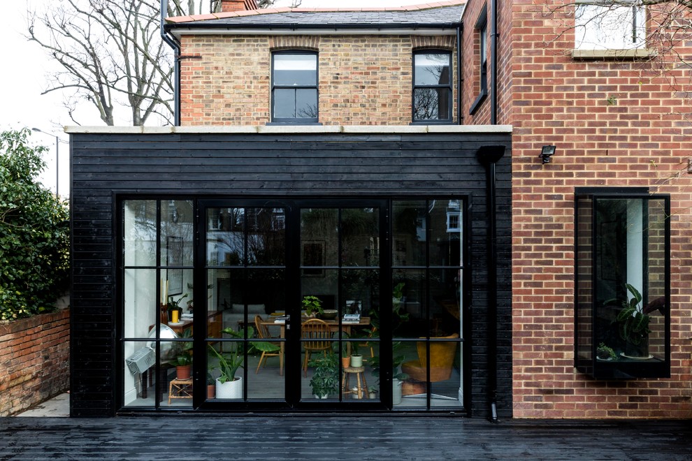Photo of a mid-sized contemporary two-storey brick red duplex exterior in London.