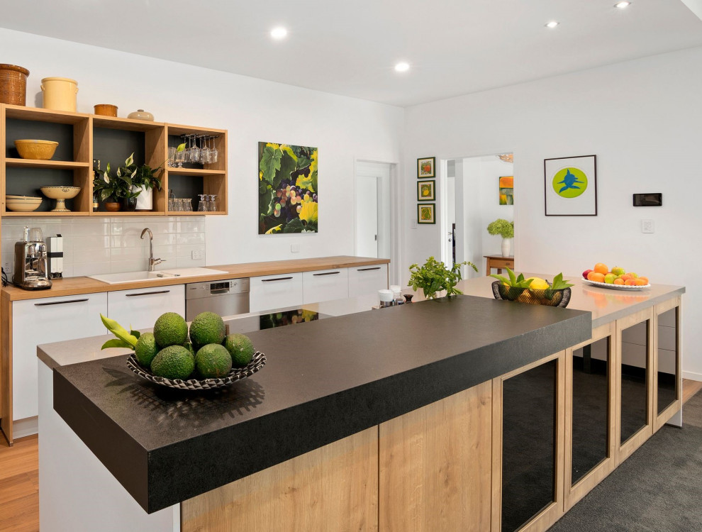 Photo of a contemporary galley eat-in kitchen in Other with a single-bowl sink, white cabinets, white splashback, ceramic splashback, stainless steel appliances and with island.