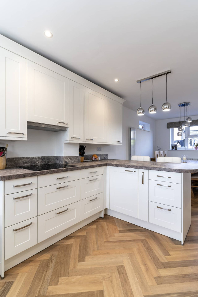 Design ideas for a small traditional u-shaped kitchen in Oxfordshire with an undermount sink, shaker cabinets, white cabinets, laminate benchtops, black appliances, a peninsula and multi-coloured benchtop.