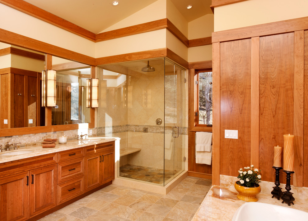 Large transitional master bathroom in Denver with a drop-in sink, raised-panel cabinets, medium wood cabinets, a corner shower, beige tile, beige walls, a drop-in tub, a two-piece toilet, stone tile, limestone floors and limestone benchtops.