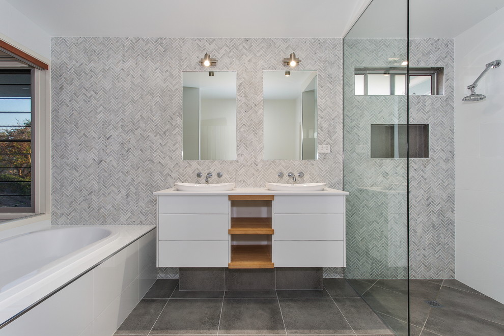 Inspiration for a contemporary bathroom in Brisbane with flat-panel cabinets, white cabinets, a drop-in tub, a curbless shower, gray tile, white tile, white walls and a vessel sink.