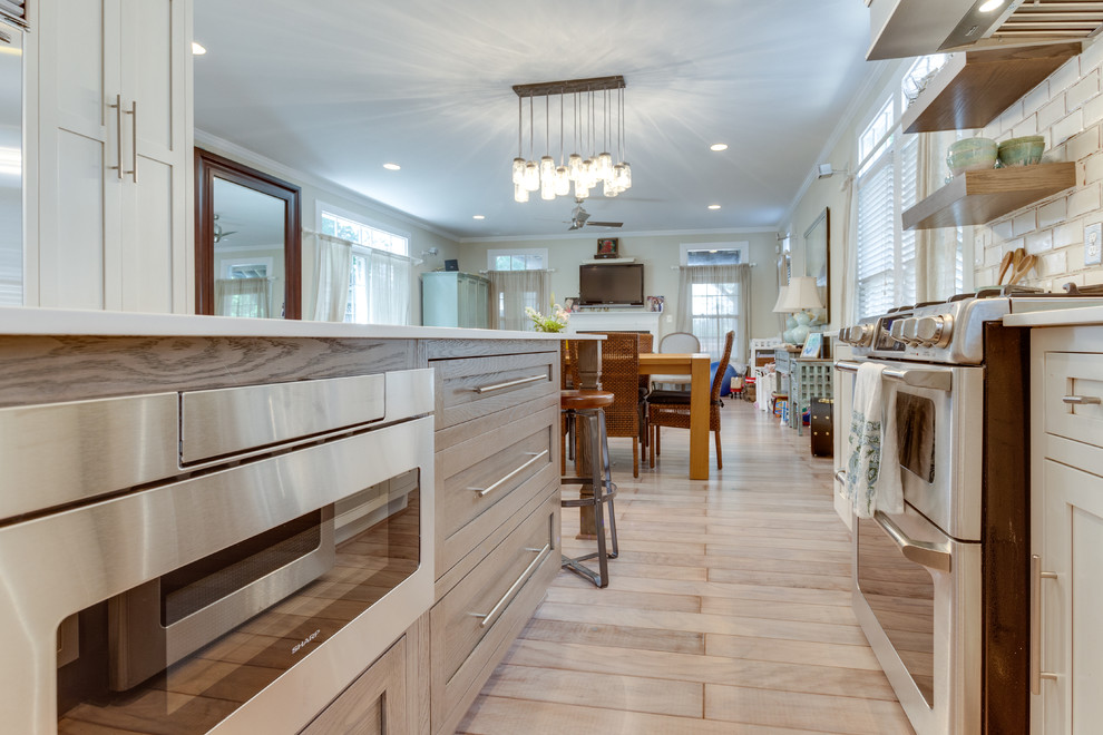 Inspiration for a mid-sized country galley kitchen in DC Metro with a farmhouse sink, laminate benchtops, stainless steel appliances, light hardwood floors and with island.