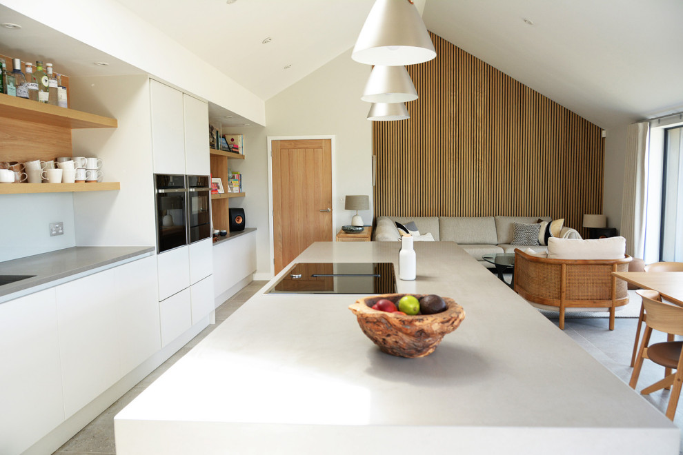 Foto på ett stort skandinaviskt grå linjärt kök med öppen planlösning, med en integrerad diskho, släta luckor, vita skåp, bänkskiva i kvartsit, vitt stänkskydd, glaspanel som stänkskydd, integrerade vitvaror, klinkergolv i porslin och grått golv