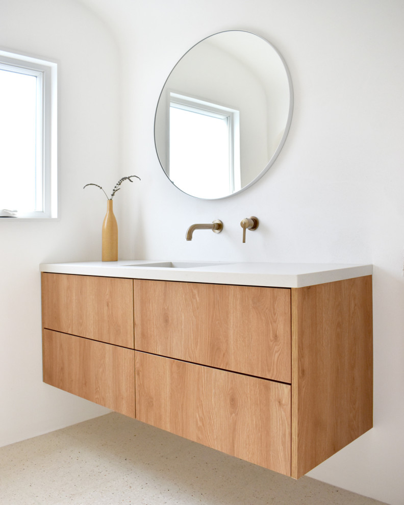 Photo of a small mediterranean master bathroom in Los Angeles with flat-panel cabinets, medium wood cabinets, an open shower, a one-piece toilet, white walls, terrazzo floors, an integrated sink, granite benchtops, multi-coloured floor, an open shower, beige benchtops, a niche, a single vanity, a floating vanity and vaulted.