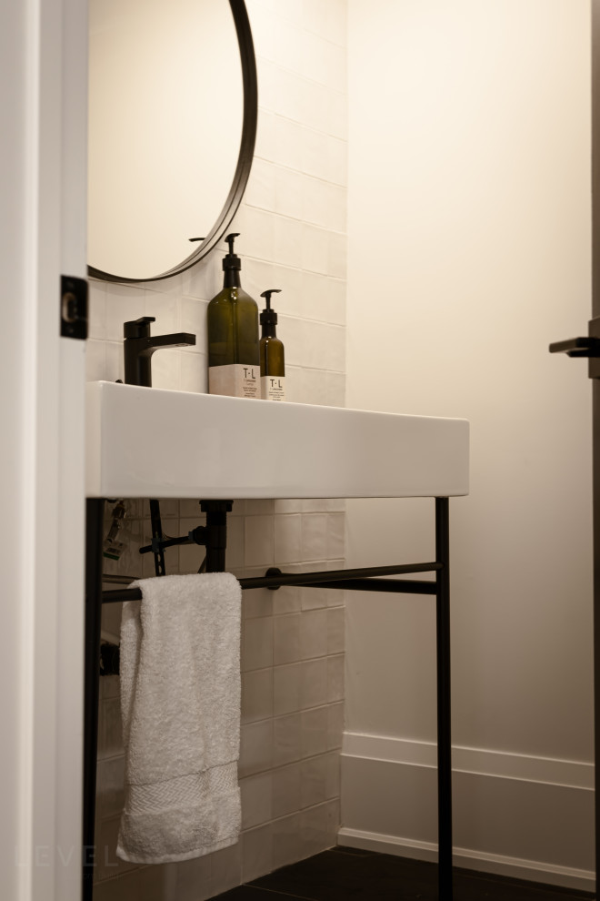 Inspiration for a small contemporary ceramic tile porcelain tile and black floor powder room remodel in Toronto with a two-piece toilet, white walls, a console sink and a freestanding vanity