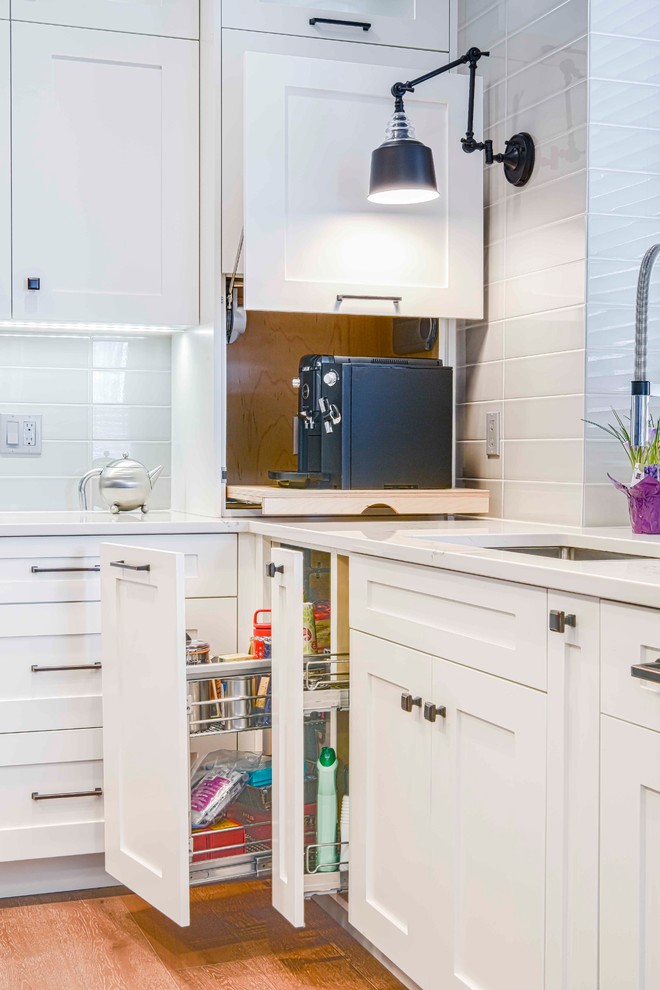 Mid-sized transitional u-shaped medium tone wood floor and brown floor home design photo in Calgary with an undermount sink, flat-panel cabinets, white cabinets, marble countertops, gray backsplash, ceramic backsplash, paneled appliances and an island