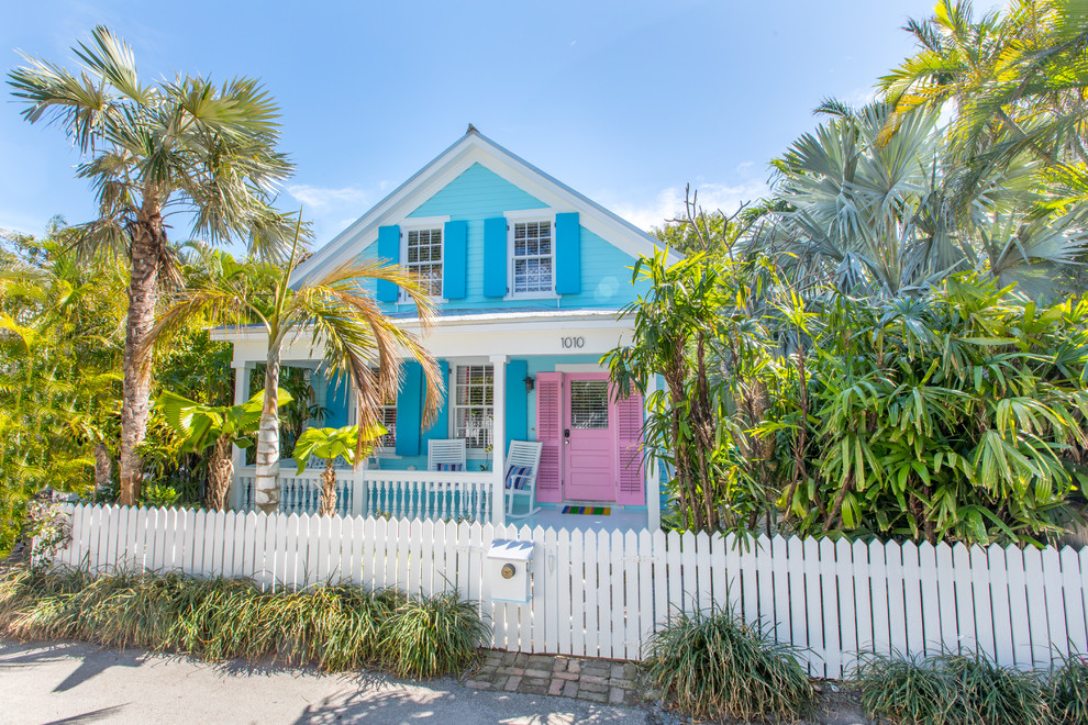 This is an example of a tropical two-storey blue house exterior in Miami with wood siding and a gable roof.