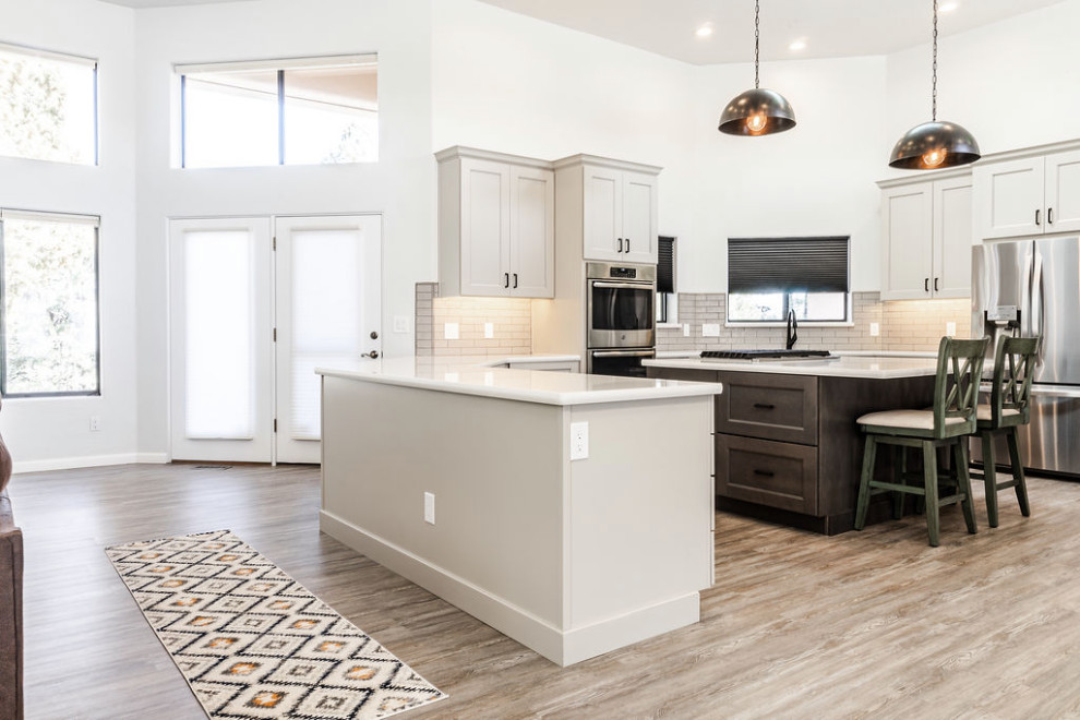 Inspiration for a large transitional u-shaped vinyl floor and gray floor eat-in kitchen remodel with an undermount sink, shaker cabinets, gray cabinets, quartzite countertops, green backsplash, subway tile backsplash, stainless steel appliances, an island and white countertops