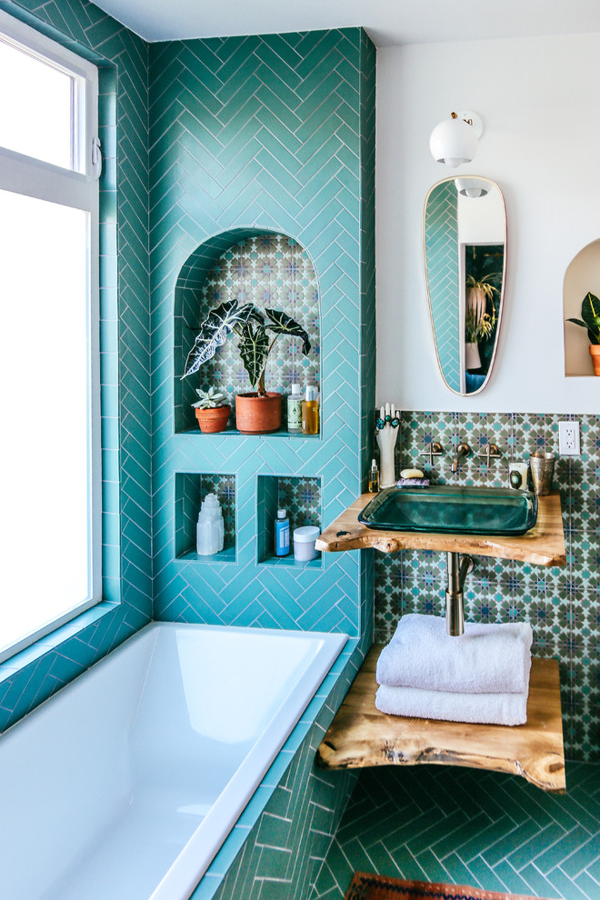 Mediterranean master bathroom in San Francisco with ceramic tile, white walls, ceramic floors, wood benchtops, open cabinets, medium wood cabinets, a drop-in tub, blue tile, a wall-mount sink, blue floor and brown benchtops.