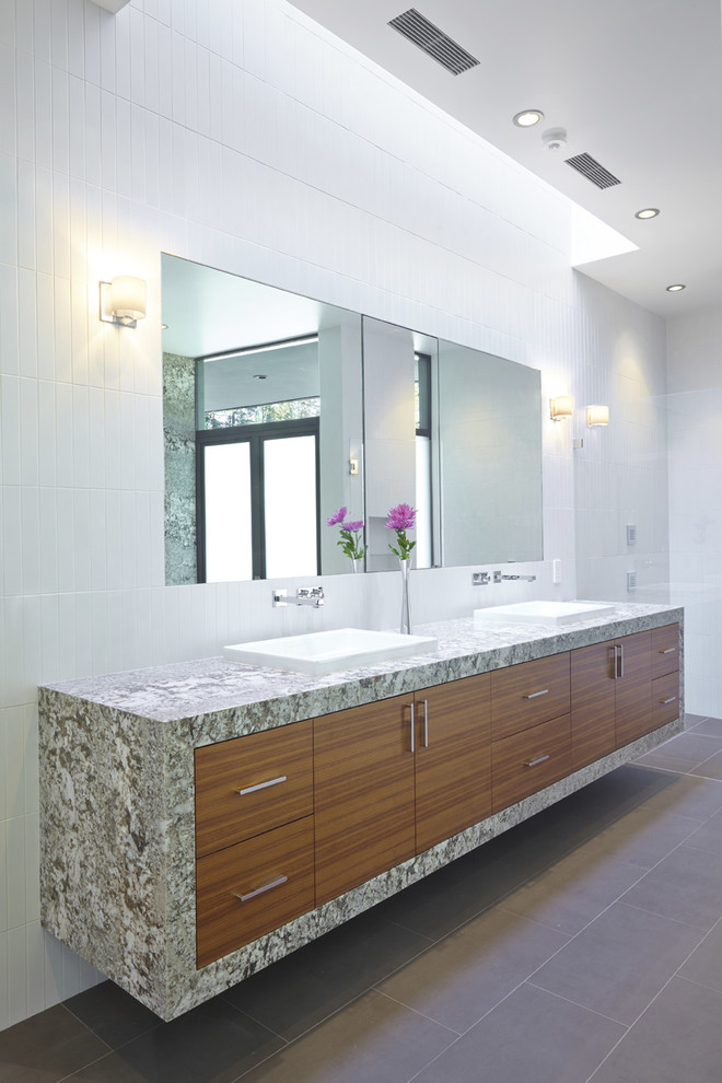 Design ideas for a large contemporary master bathroom in San Francisco with a drop-in sink, flat-panel cabinets, medium wood cabinets, granite benchtops, an undermount tub, a wall-mount toilet, white tile, porcelain tile, white walls, porcelain floors and grey floor.