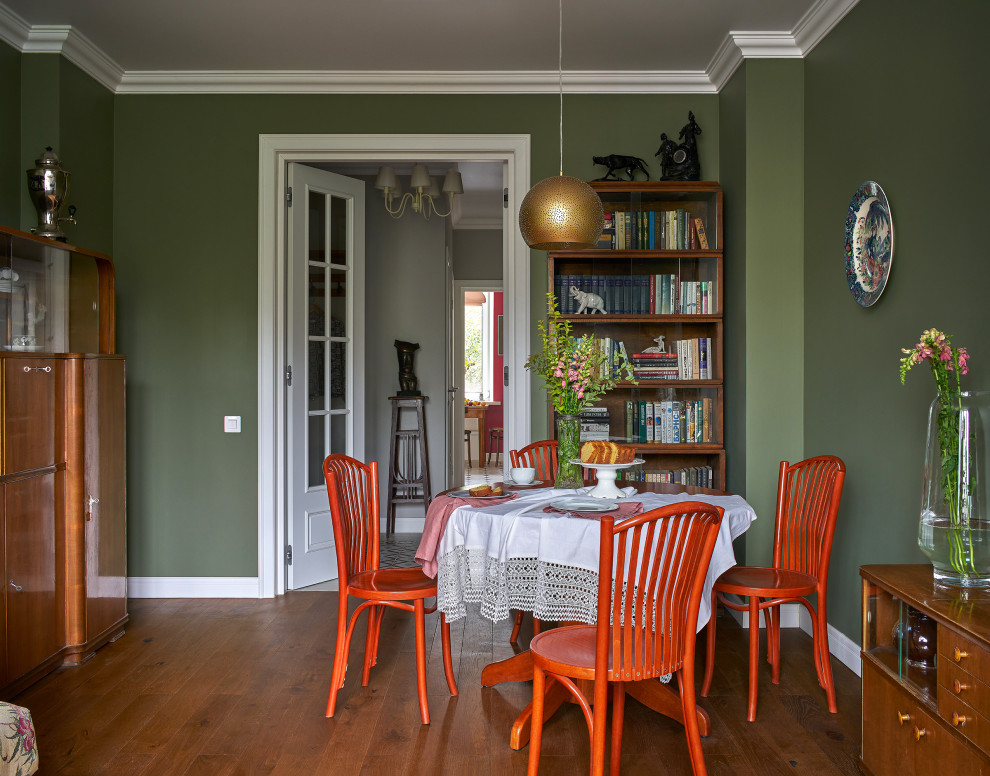 Idee per una sala da pranzo bohémian chiusa e di medie dimensioni con pareti verdi, pavimento in legno massello medio, camino classico, cornice del camino in intonaco, pavimento marrone, travi a vista e carta da parati