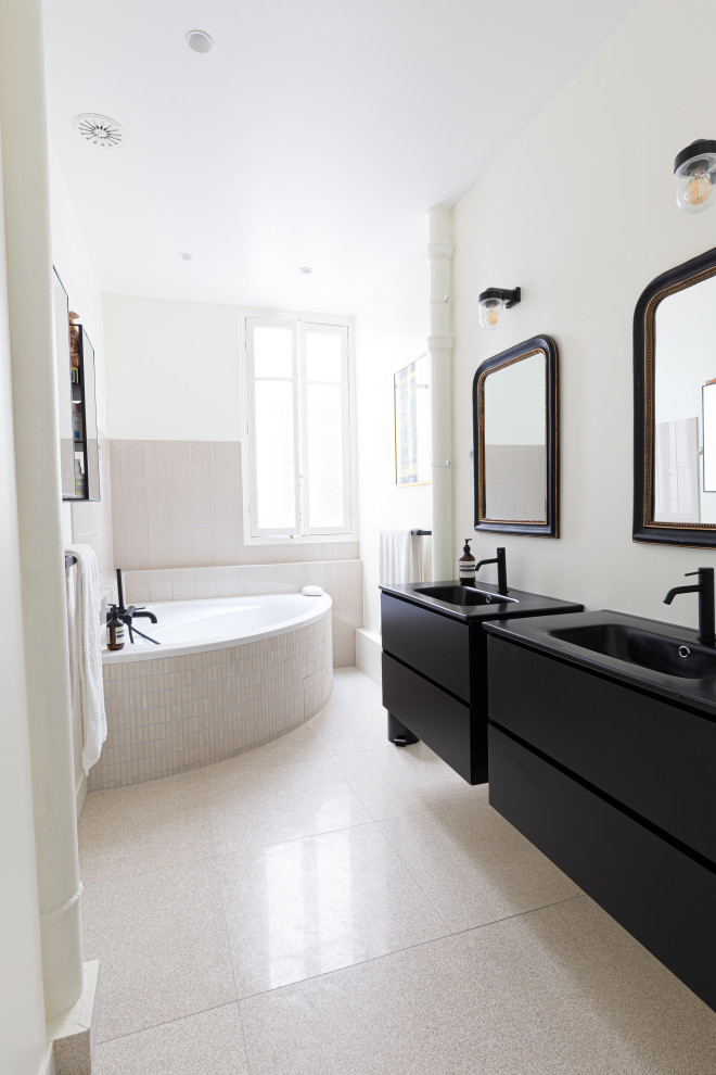 Immagine di una grande stanza da bagno padronale classica con vasca ad angolo, piastrelle beige, pareti beige, pavimento alla veneziana, lavabo a consolle, top in laminato, pavimento beige, top nero e due lavabi