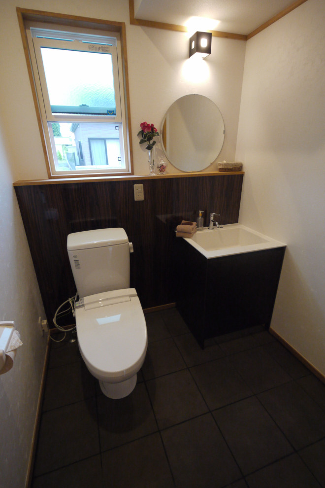 Photo of a large traditional powder room in Other with flat-panel cabinets, brown cabinets, a one-piece toilet, white tile, glass sheet wall, white walls, porcelain floors, an integrated sink, solid surface benchtops, brown floor, white benchtops, wallpaper and panelled walls.