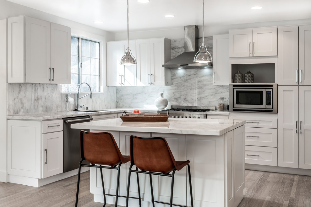 This is an example of a mid-sized transitional eat-in kitchen in San Francisco with an undermount sink, shaker cabinets, white cabinets, marble benchtops, multi-coloured splashback, stone slab splashback, stainless steel appliances, light hardwood floors, with island and beige floor.